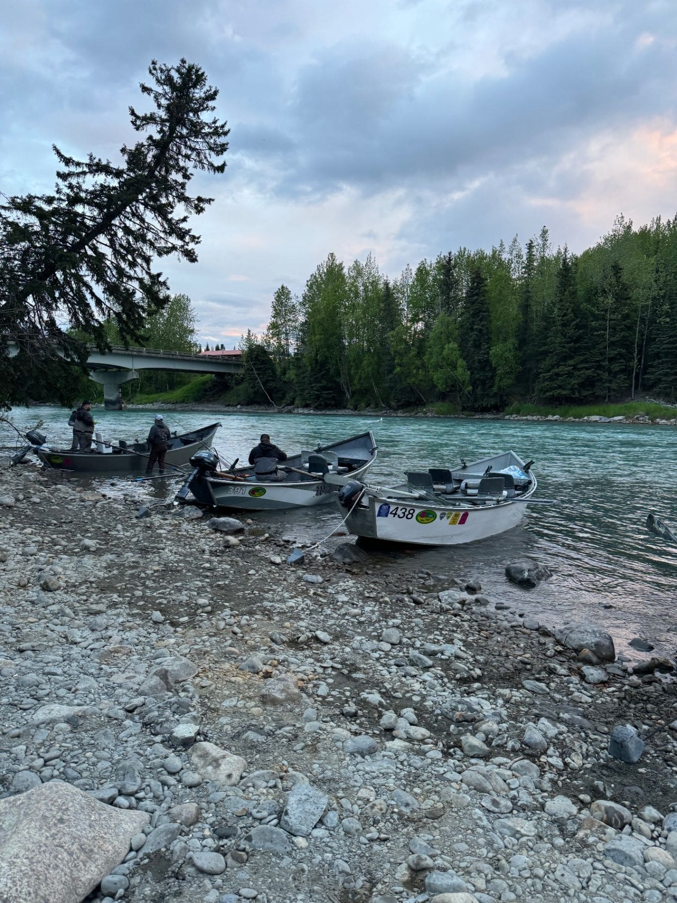 Fishing boats lined up on the rocky Kenai River bank at dusk