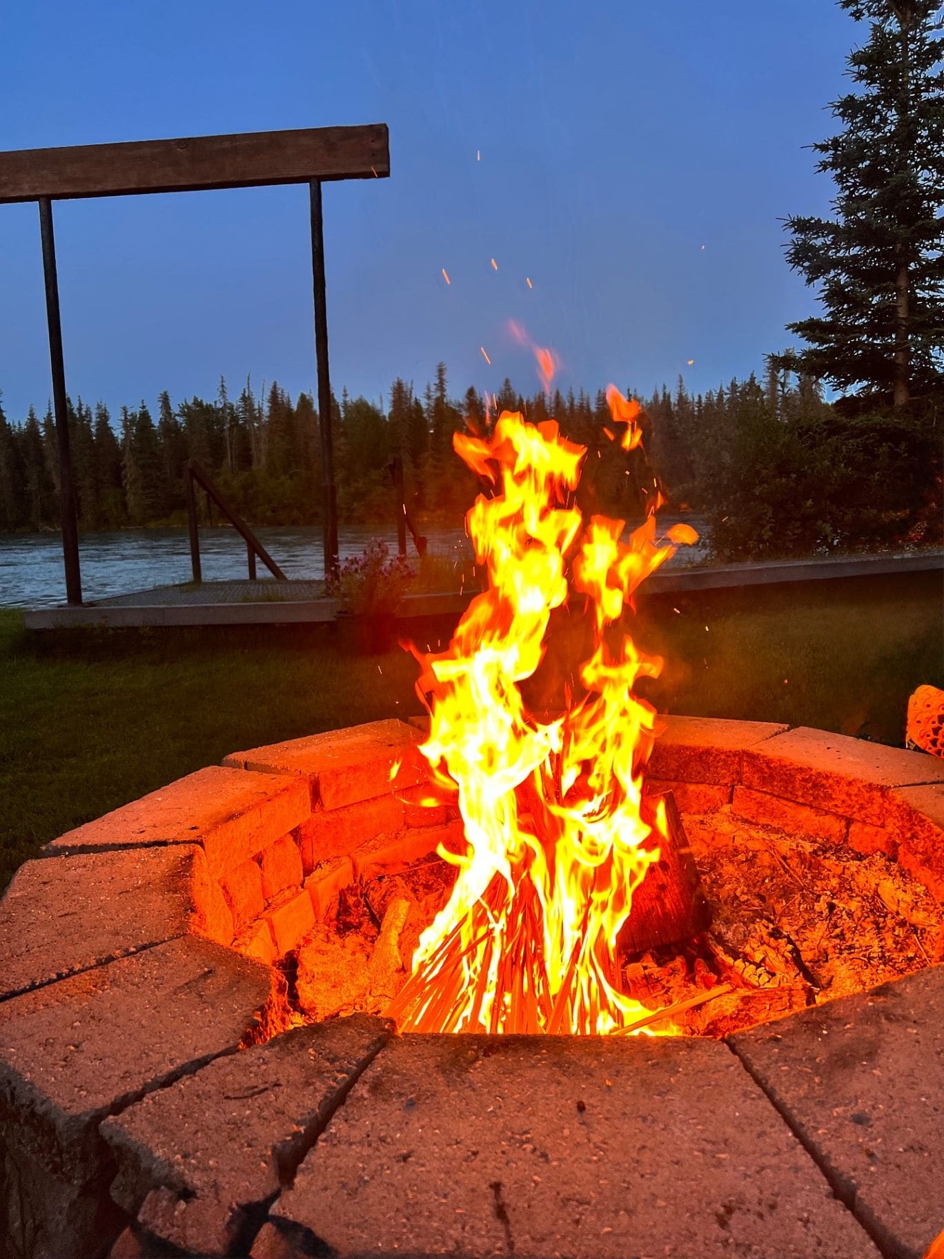 Campfire blazing by the river at the lodge