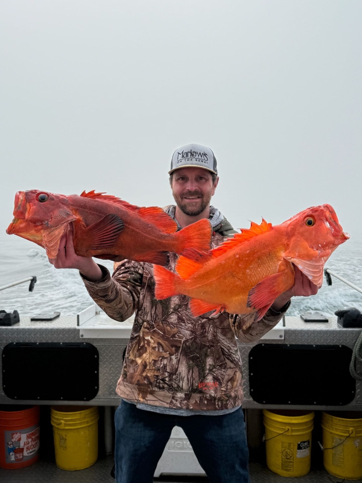 Angler holding two bright rockfish on a charter boat