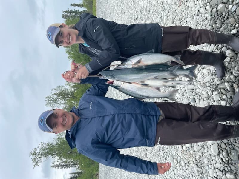 Couple showing off their salmon catch on the gravel bar