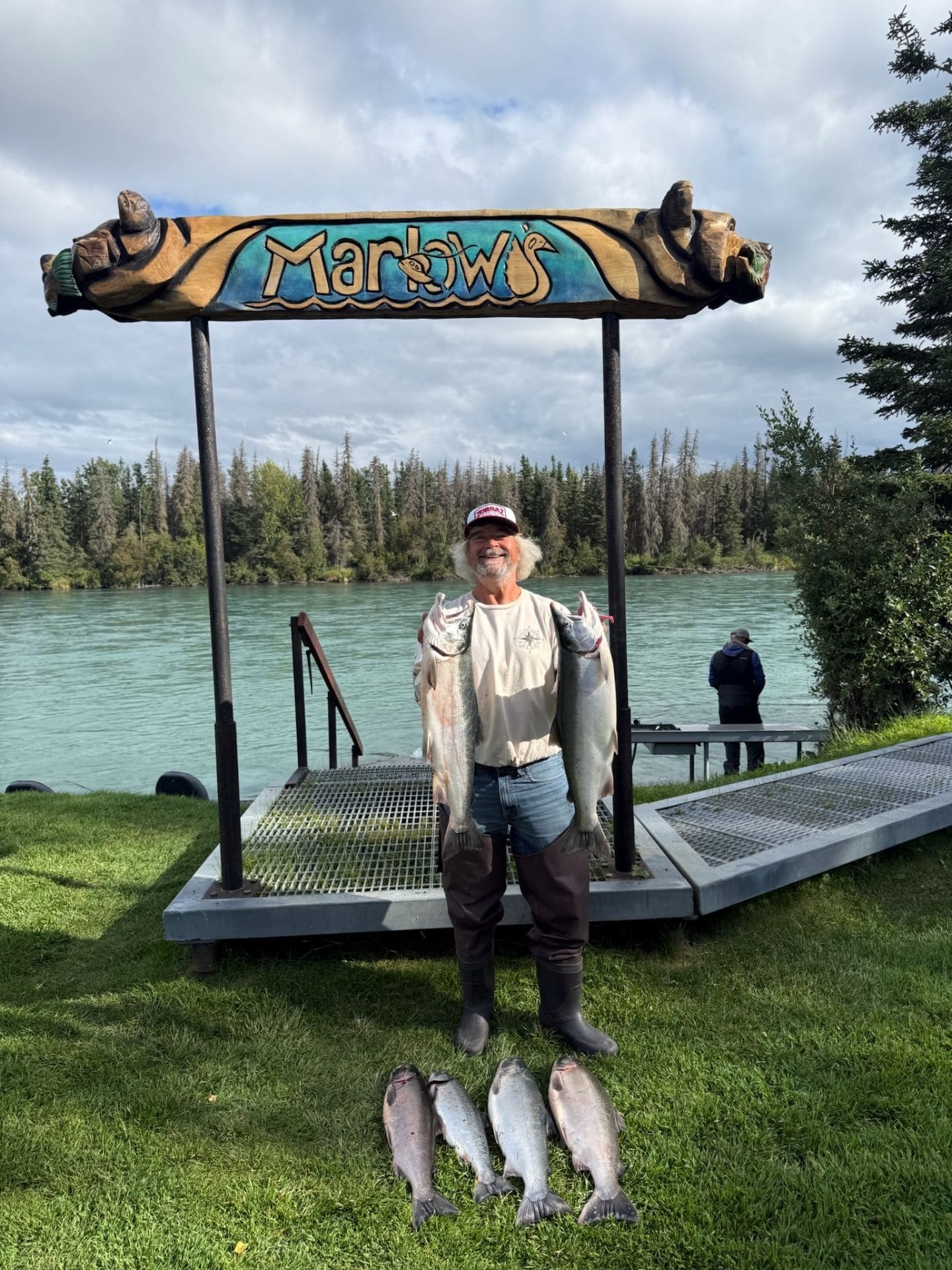 Angler holding two silver salmon under the Marlow's sign