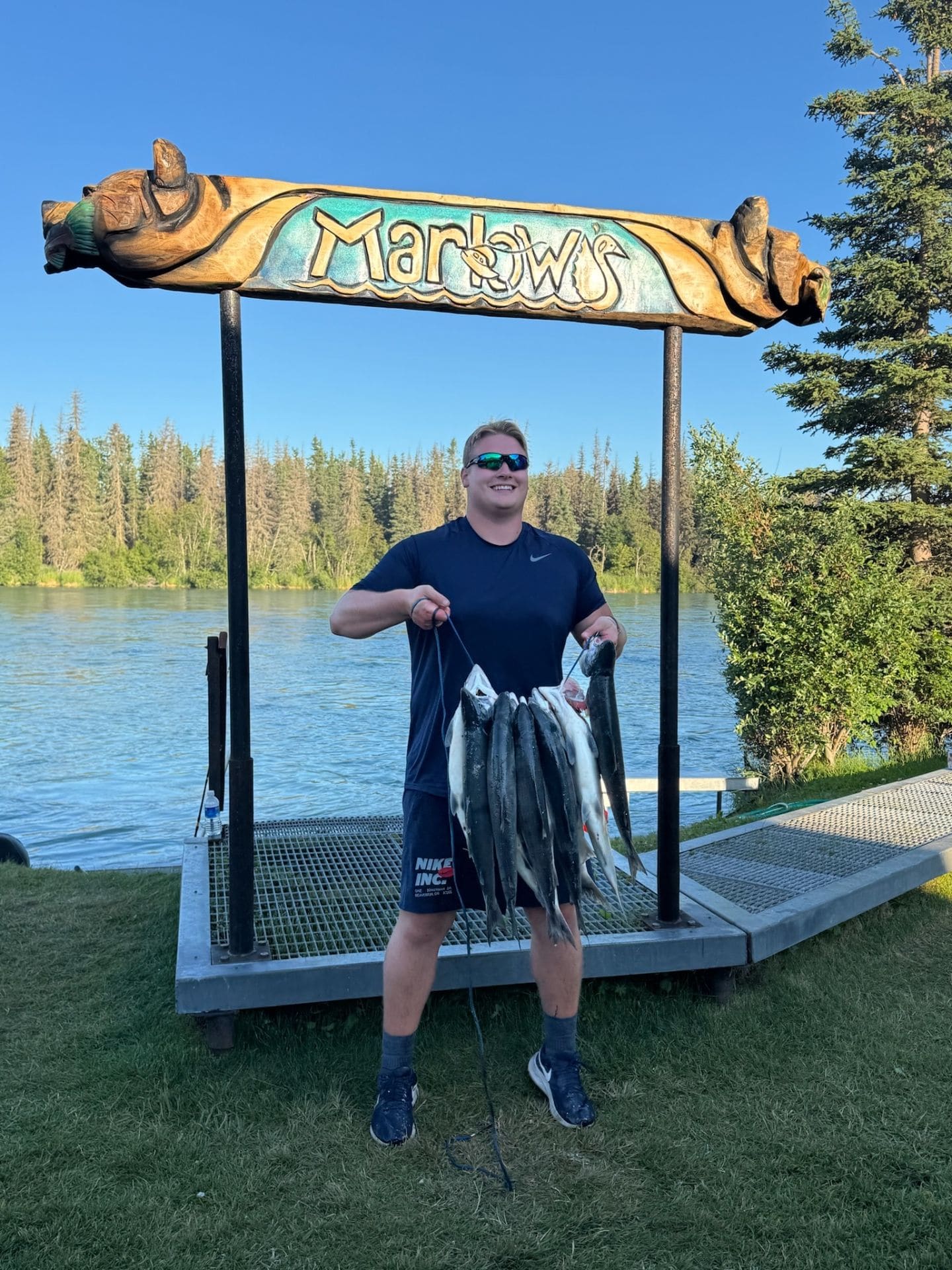 Young angler with a full stringer of salmon under the Marlow's sign