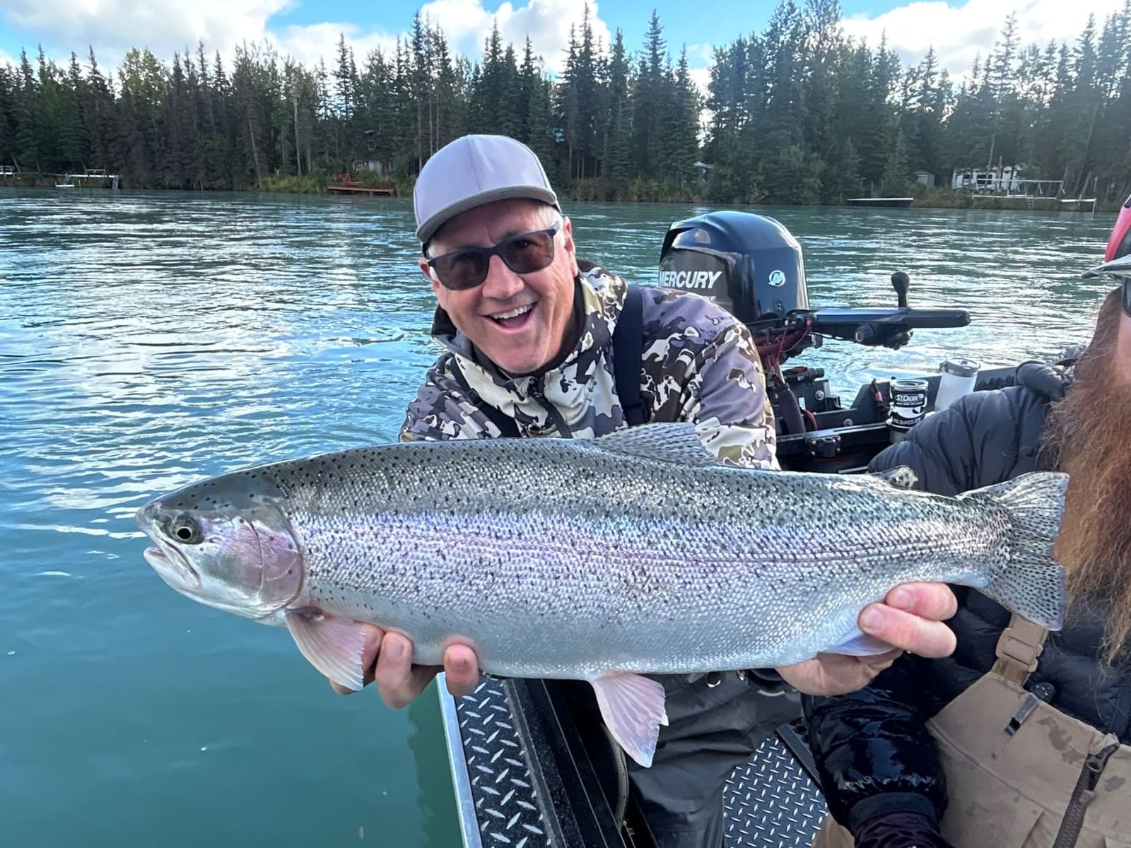 Happy angler with a large rainbow trout caught from the motor boat