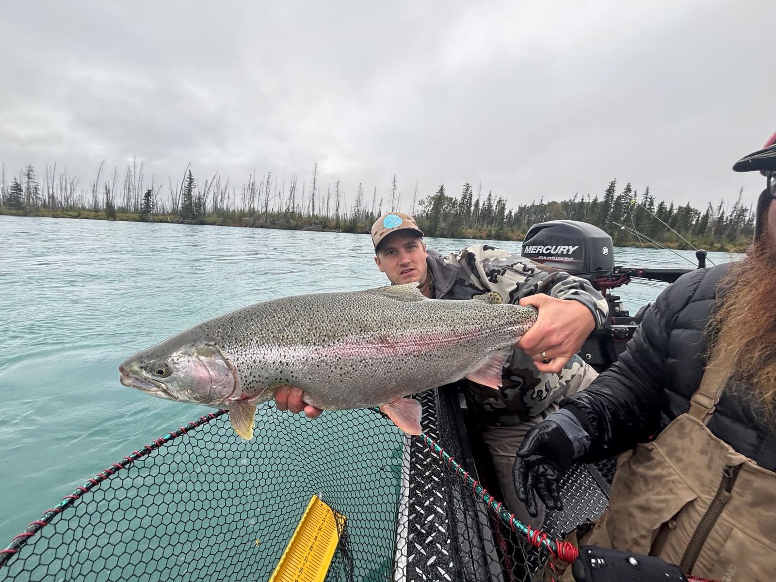 Angler holding a trophy rainbow trout from the motor boat on the Kenai River
